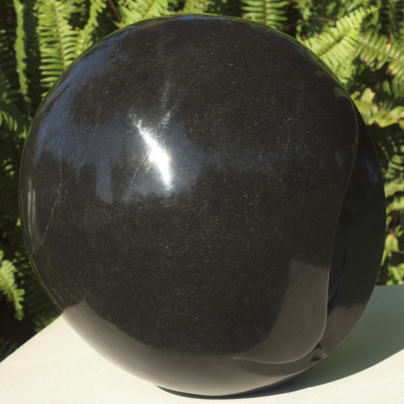 Round head black stone sculpture - 'Hiding My Face' by famous artist Nesbert Mukomberanwa from Zimbabwe - front left