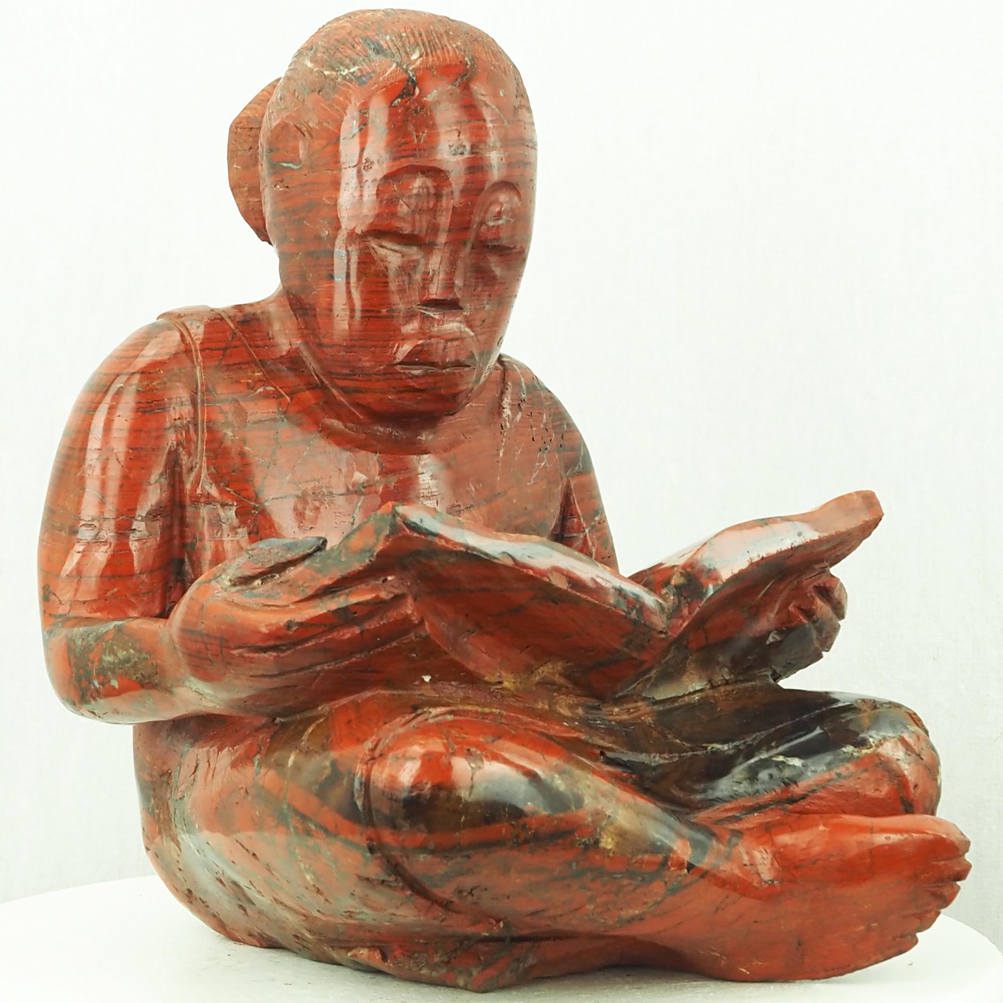 Sculpture child girl reading red stone - Doing My Homework by Jonathan Mhondorohuma - front left