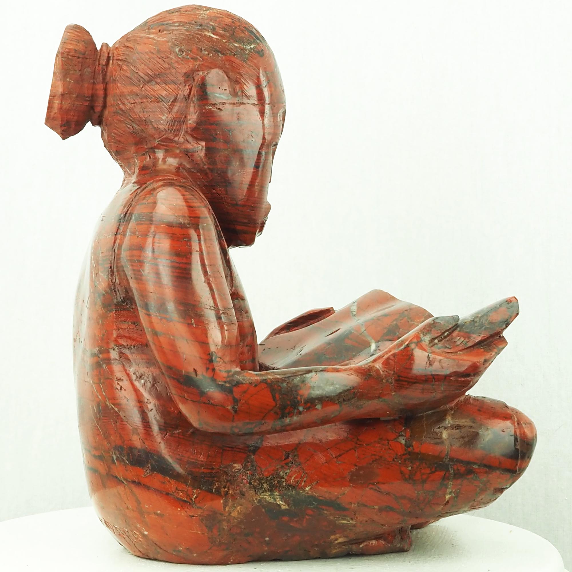 Sculpture child girl reading red stone - Doing My Homework by Jonathan Mhondorohuma - left side