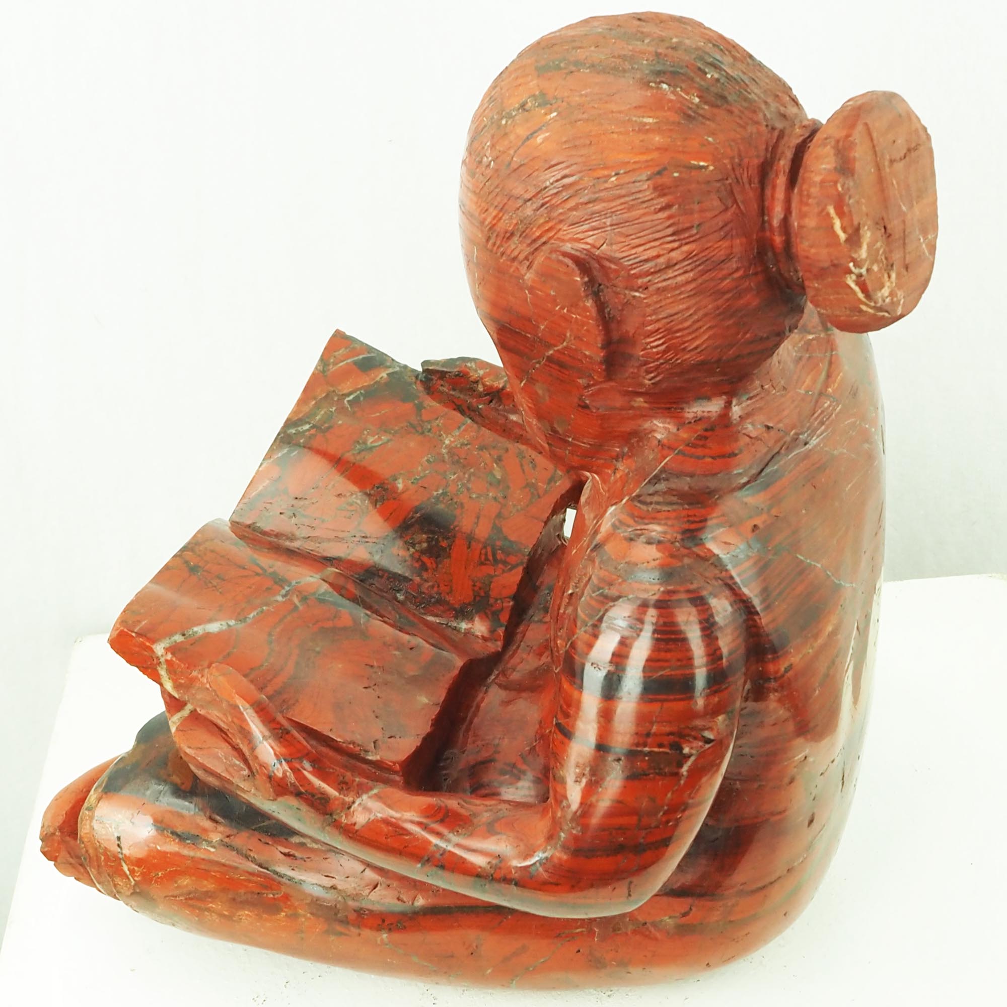 Sculpture child girl reading red stone - Doing My Homework by Jonathan Mhondorohuma - right side from above